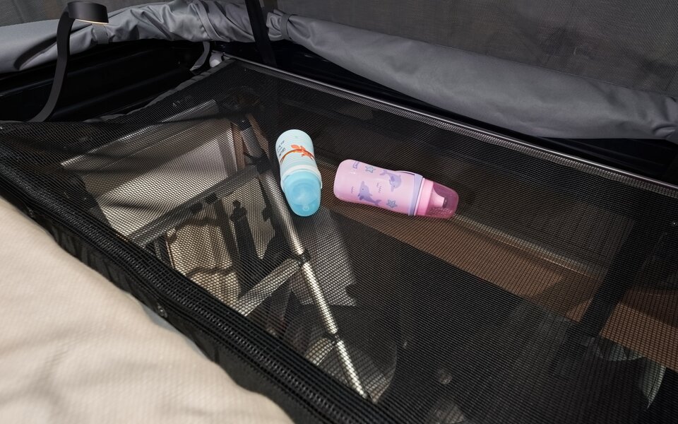 Espace de rangement dans le toit relevable d’un camping-car Carado avec filet de rangement, deux bouteilles d’eau et structure pliée