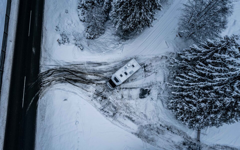 Carado motorhome seen from above on a snow-covered forest driveway near the road