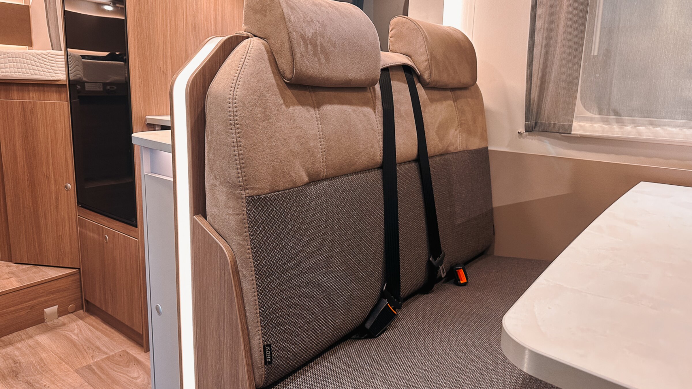 Banquette dans le camping-car Carado avec deux appuie-tête, des ceintures de sécurité et une table au coin repas