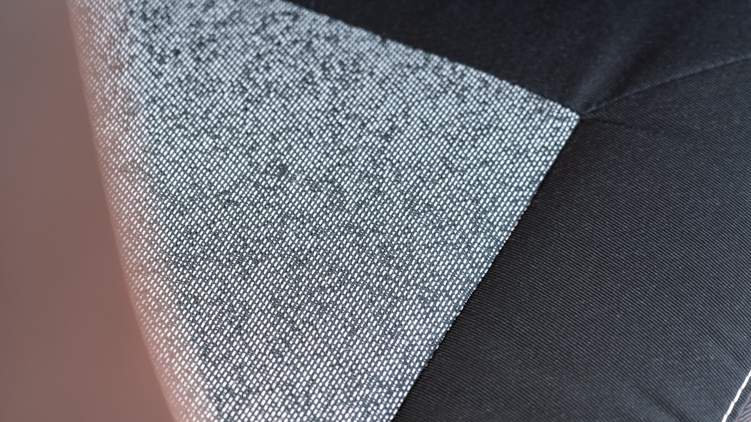Gros plan sur un tissu de revêtement gris à motif, à côté d’un tissu noir avec surpiqûre décorative dans le camping-car Carado