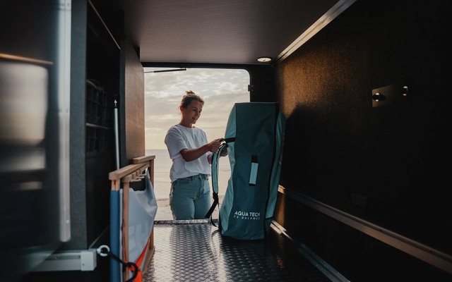 Man unloading a mountain bike from the rear garage of a HYMER motorhome