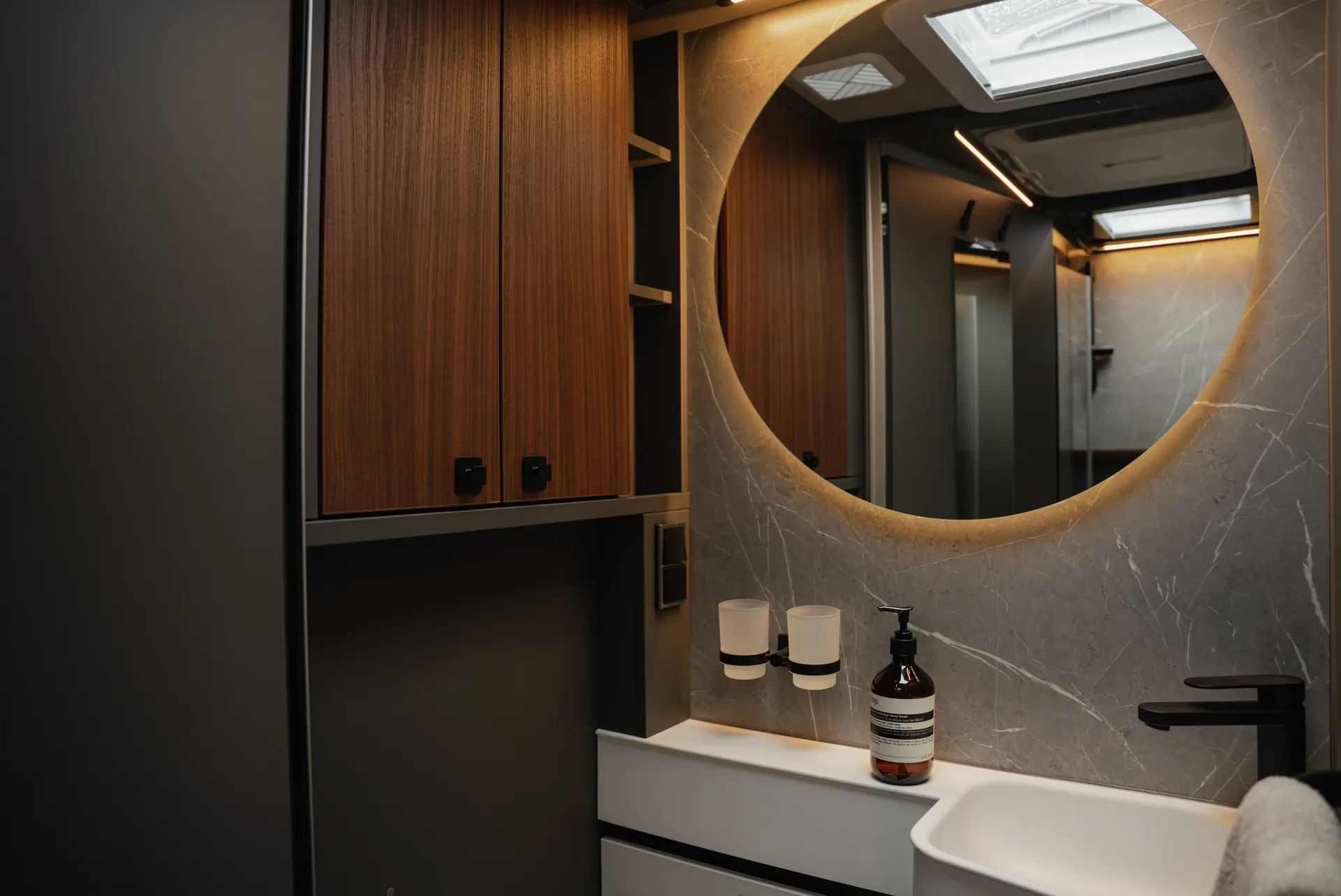 The illuminated round mirror, premium surfaces and precise details create an atmosphere that harmoniously combines homeliness and quality.