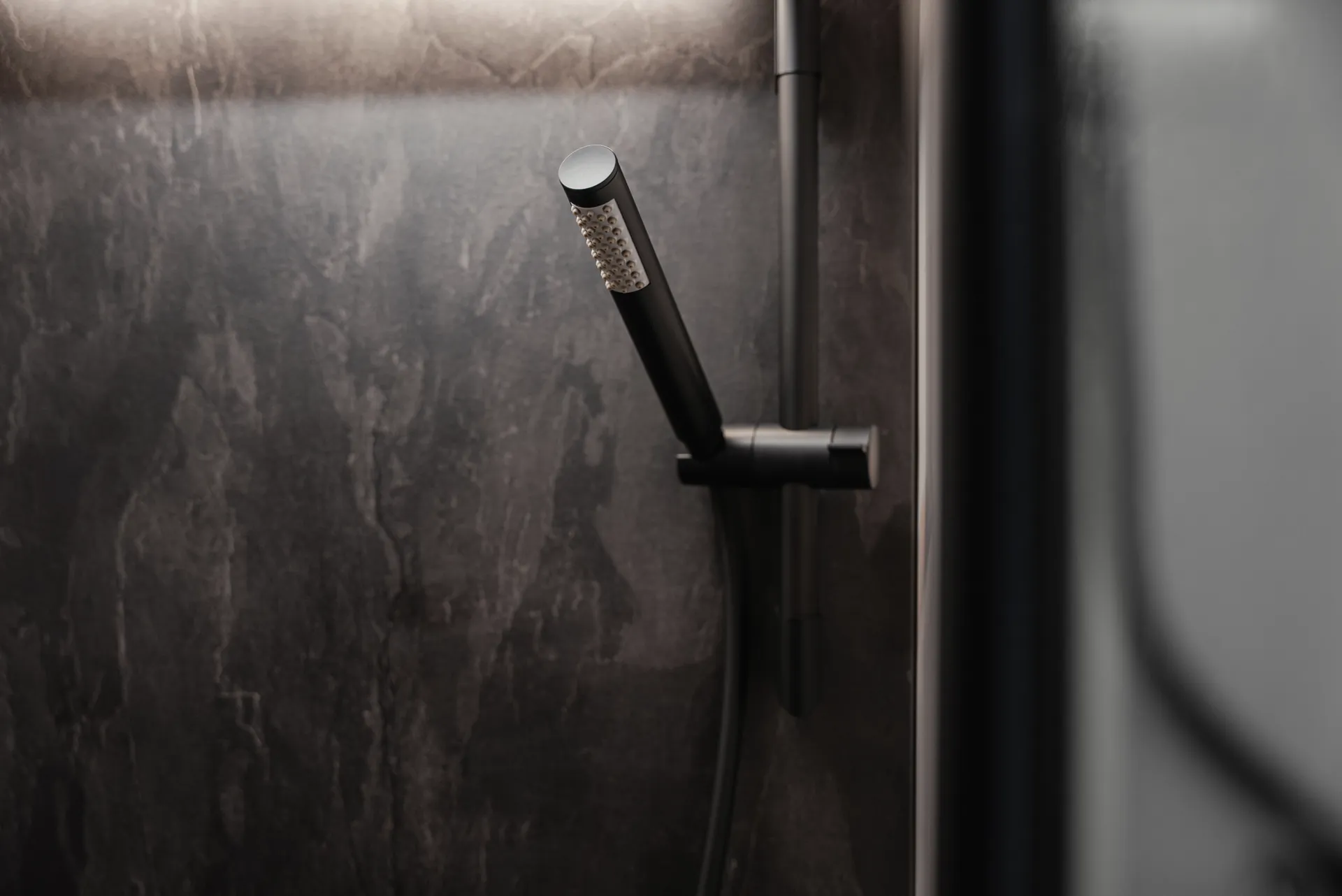 Matt black fittings, modern surfaces and indirect lighting accents give the shower area its clear, homely character.