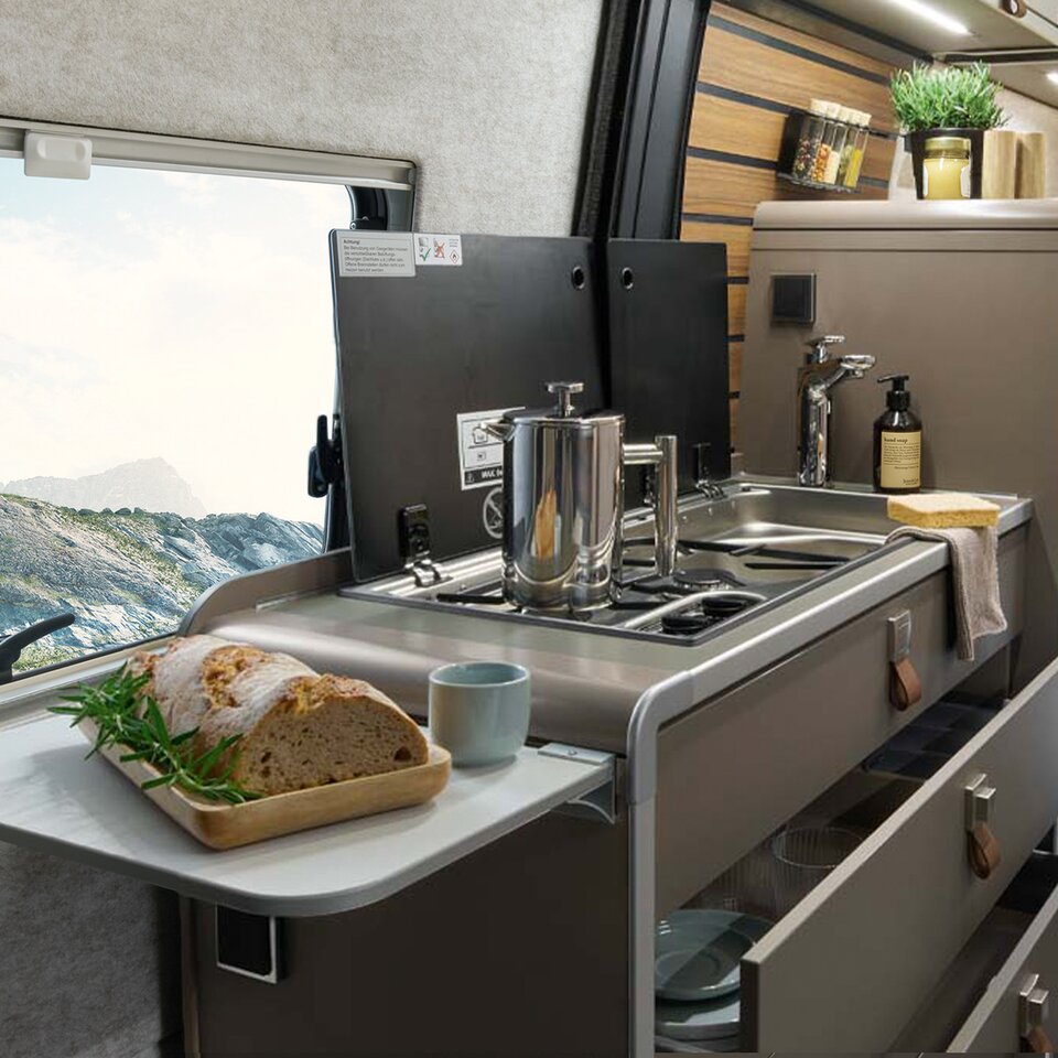 On the kitchen extension in the HYMER Grand Canyon S, there is bread. In the background, the kitchenette with stove, sink, and refrigerator is visible.