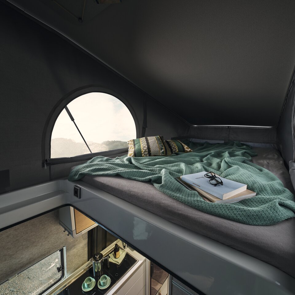 The additional sleeping place in the pop-top roof is visible. Left and right, you can look out through the windows in the roof.