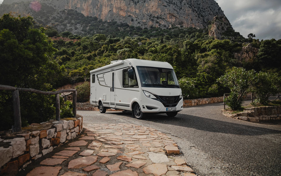 Hymer B‑MC I in a striking three‑quarter front view with modern exterior design and integrated premium architecture against an impressive mountain backdrop