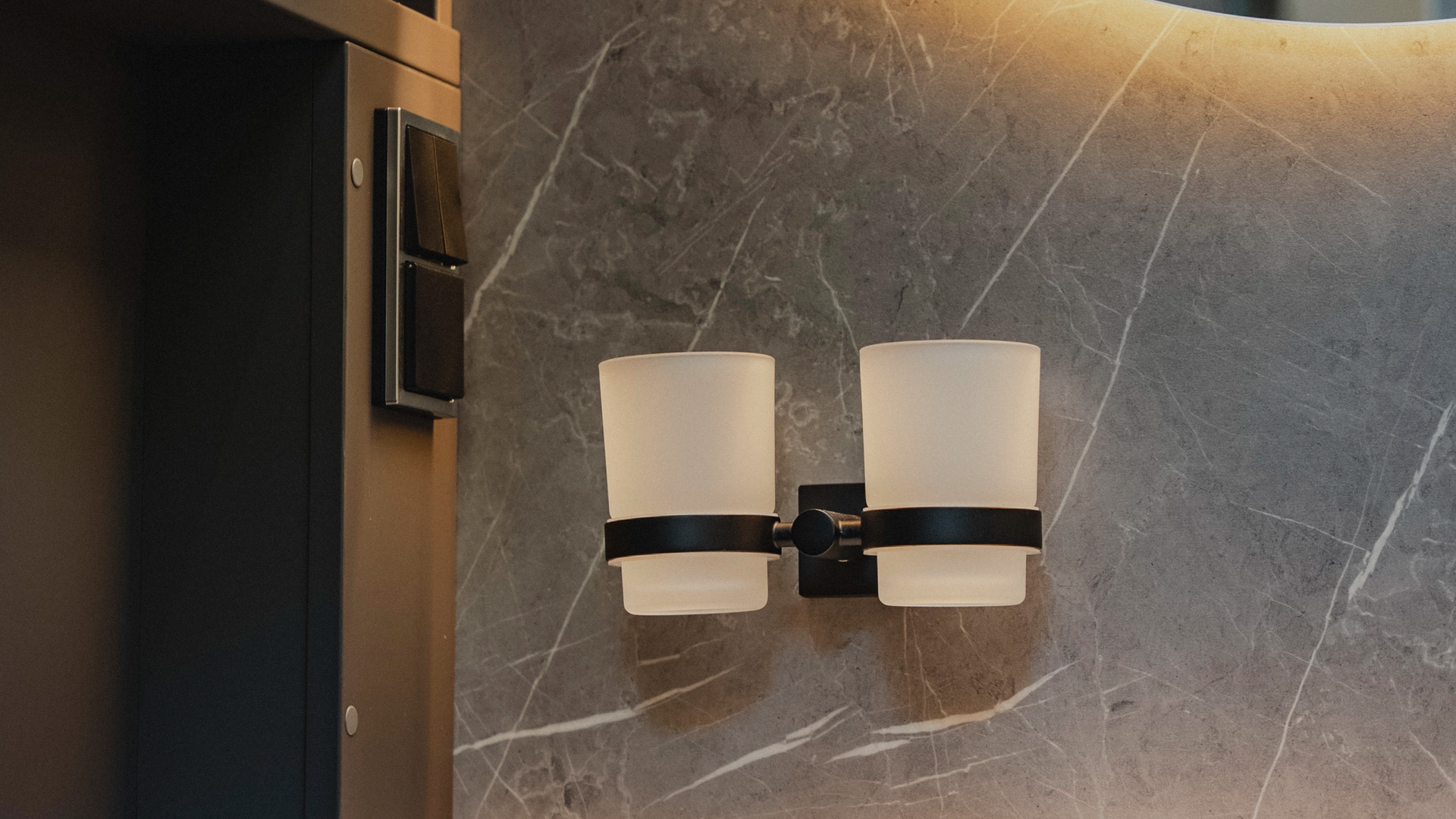 Thoughtful details stylishly implemented: The cup holder blends with the noble surface of the side wall, the modern washbasin, and the backlit, round mirror to form a harmonious overall artwork.