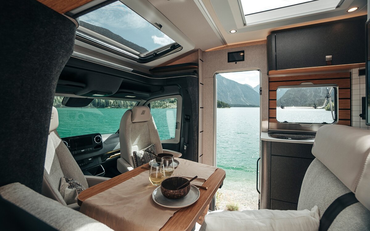 En regardant à travers l'intérieur du HYMER ML-T dans le monde du style Native Bamboo, de nombreuses fenêtres et portes offrent une vue sur le paysage.