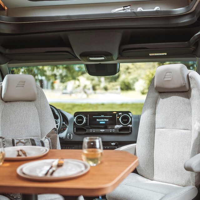 Derrière les sièges conducteur retournés du HYMER ML-T se trouve le système multimédia Mercedes Benz.