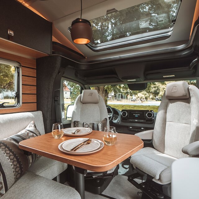 La table du salon du HYMER ML-T est dressée. La lampe multifonctions est montée au-dessus de la table.