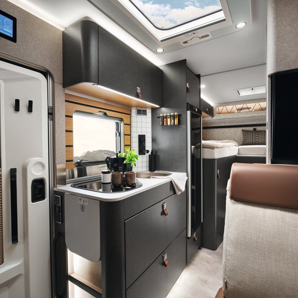 On the stove in the HYMER ML-T in the Velvet Ash style world, there is a pot. In front of it, partially visible, is the door, and above it is the HYMER Connect display.
