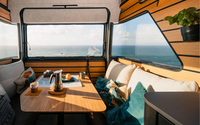 On the table in the Magic Diner of the HYMER Venture S, there are a camera, fruit, and an espresso pot.