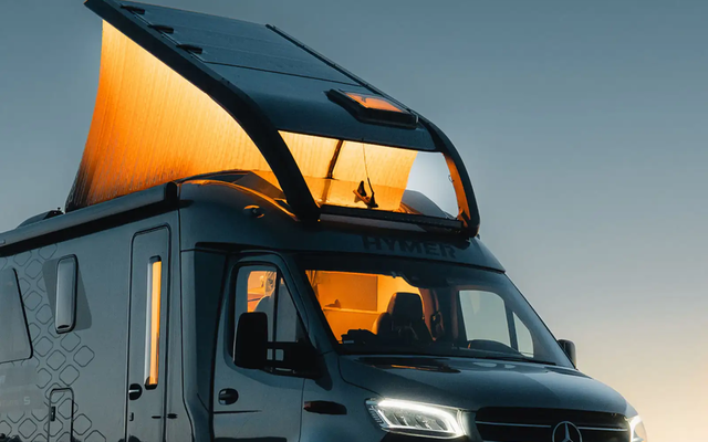 The HYMER Venture S is seen in the twilight. The Instant Loft is illuminated.