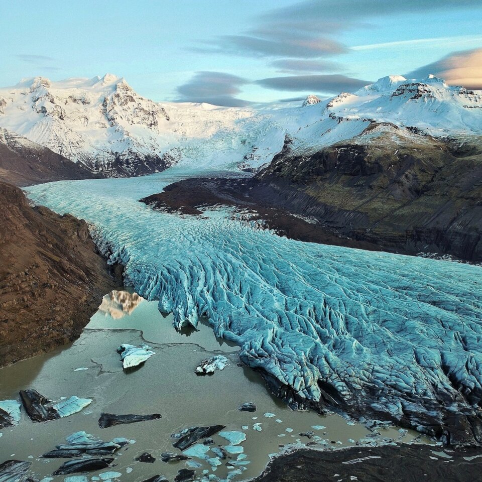 Vue d'un paysage originel avec glace, neige et montagnes sous un ciel légèrement nuageux, photographié lors d'un voyage en camping-car en Islande.