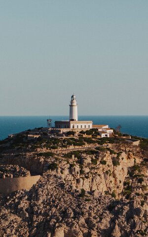 View of the lighthouse standing on a hill, with the sea in the background.