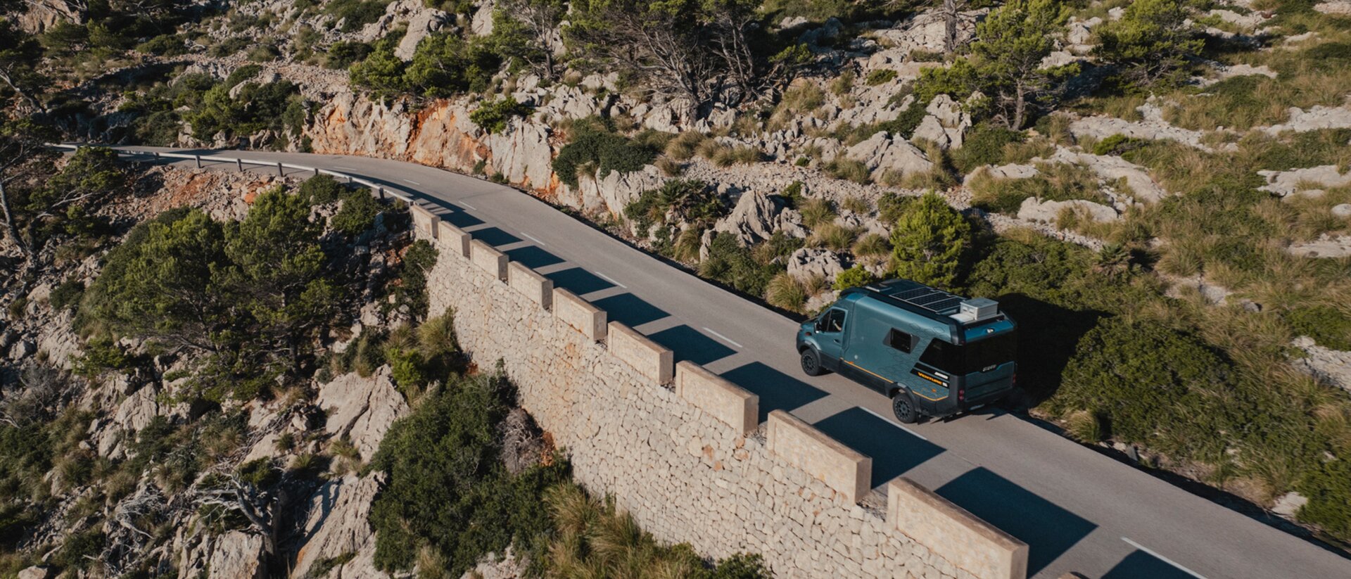 Aerial view of the Venture S driving down winding roads, with rocks and trees in the background.